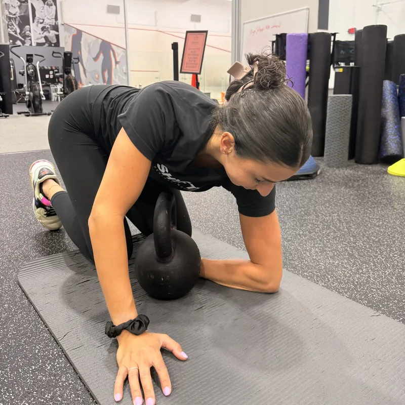 A client doing a kettlebell exercise on a mat in the gym